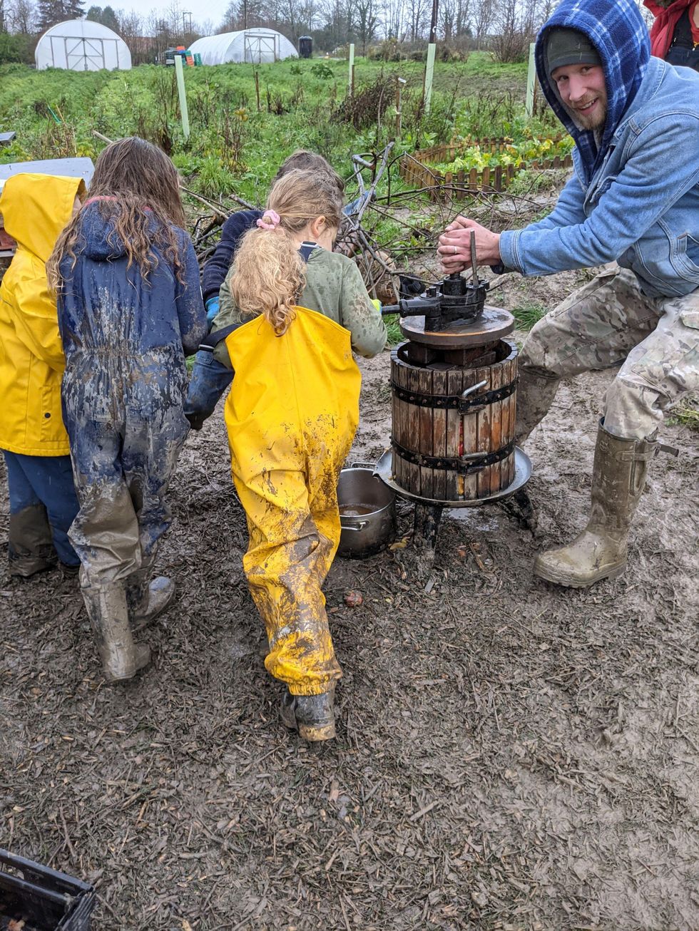 Children using an apple press on the farm